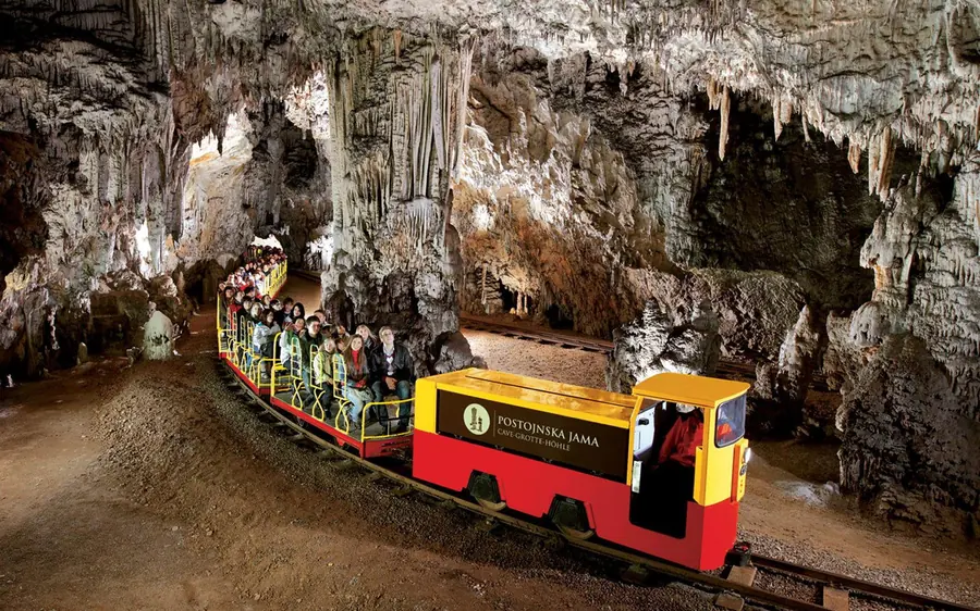 The red and yellow cave train standing in a rock tunnel hung with stalactites
