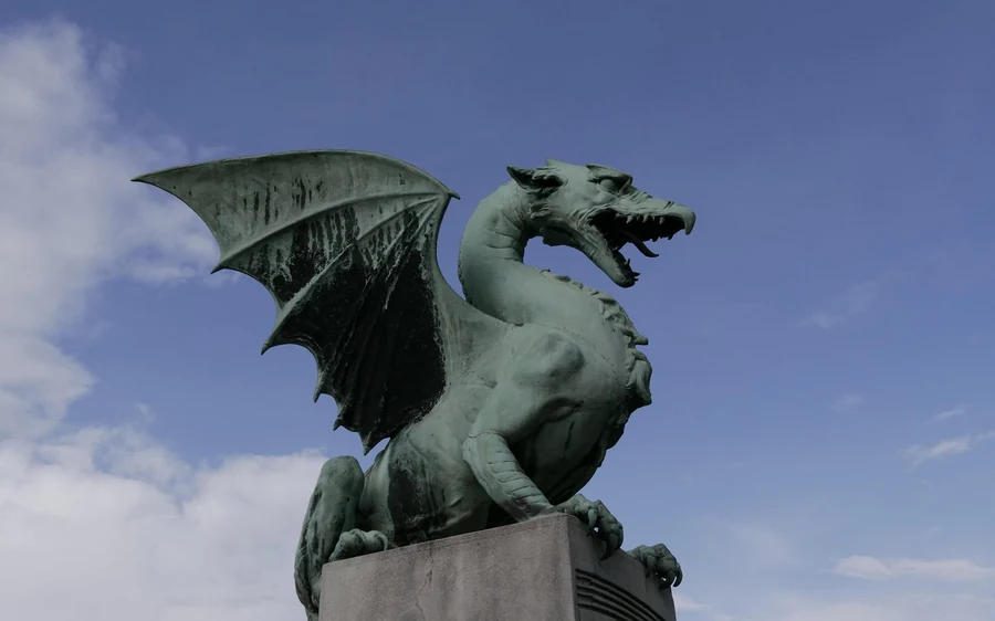 The bronze dragon of the Ljubljana dragon bridge on its stone pedestal